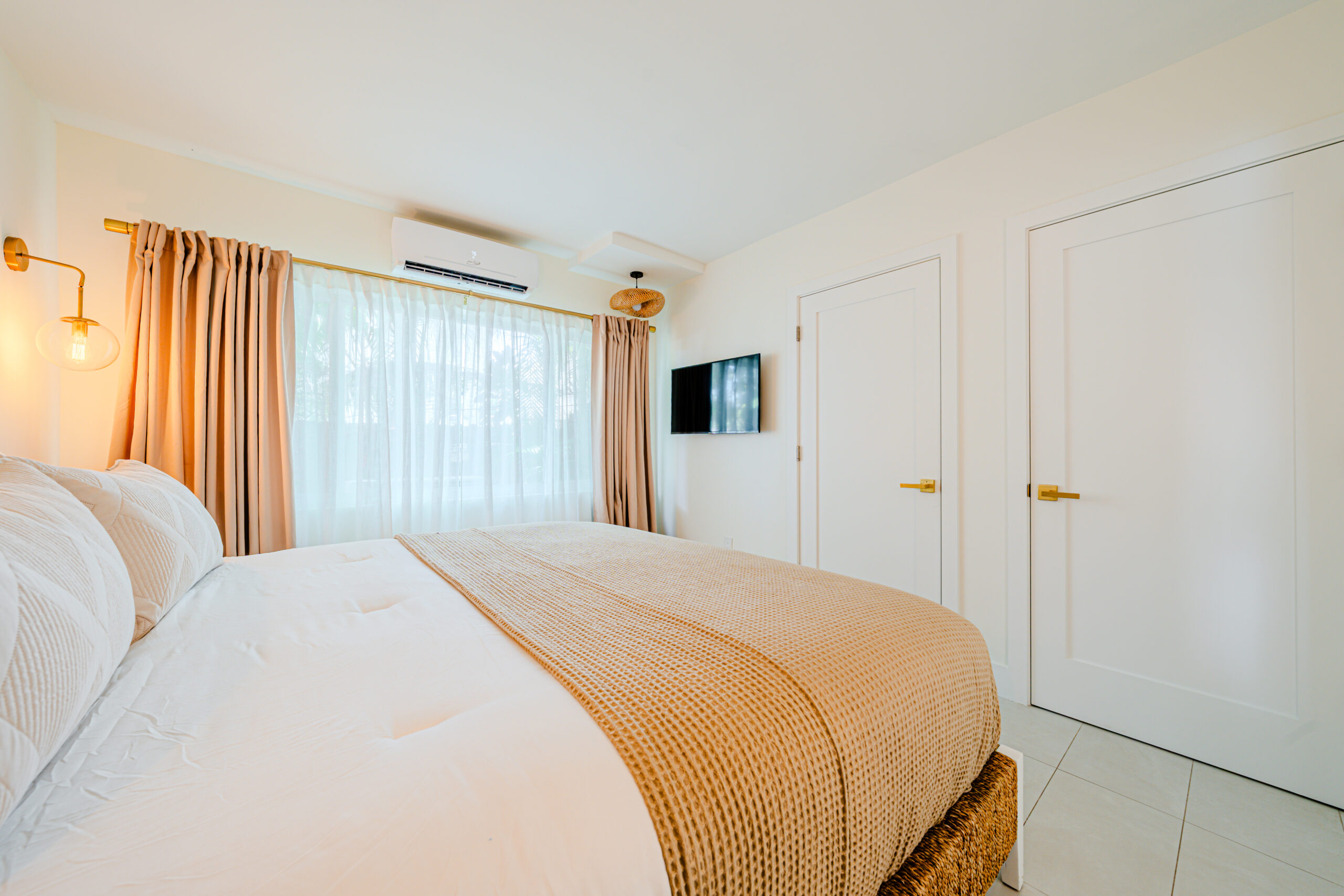 A hotel room with a bed, TV, and window