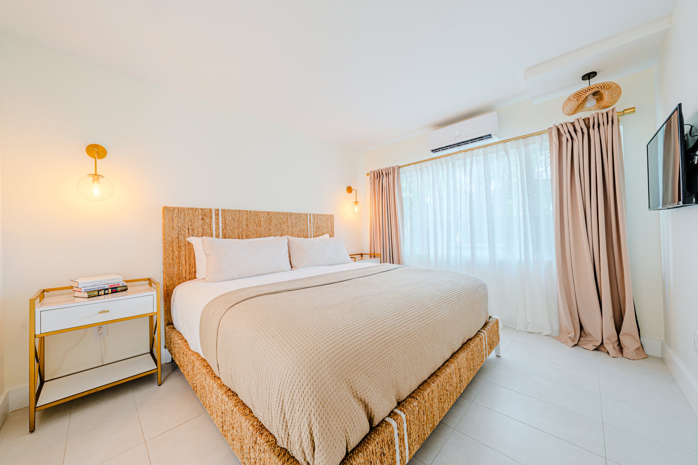 A hotel room with a large bed, nightstand, and TV on the wall.