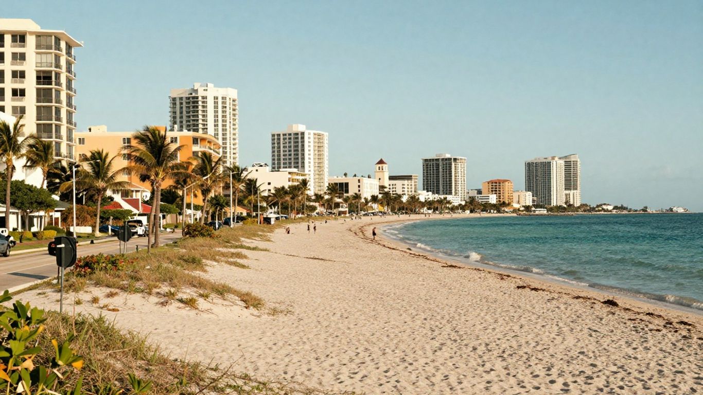 A beach with palm trees and buildings in the background.